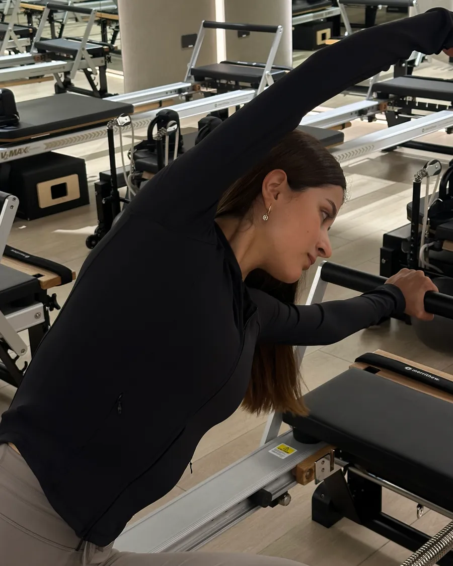 A side stretch on the reformer at The Reformr Pilates Studio, Shams Boutik